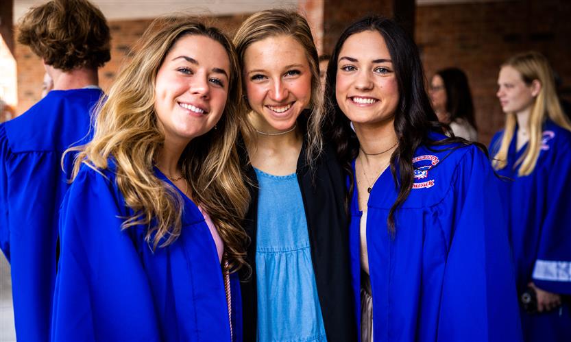 Three graduating seniors smile